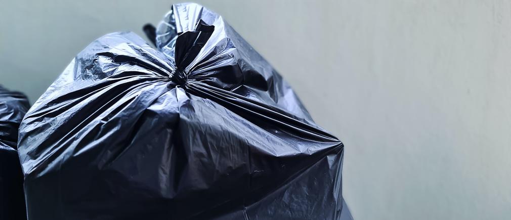 Mains tenant un sac poubelle noir Handybag