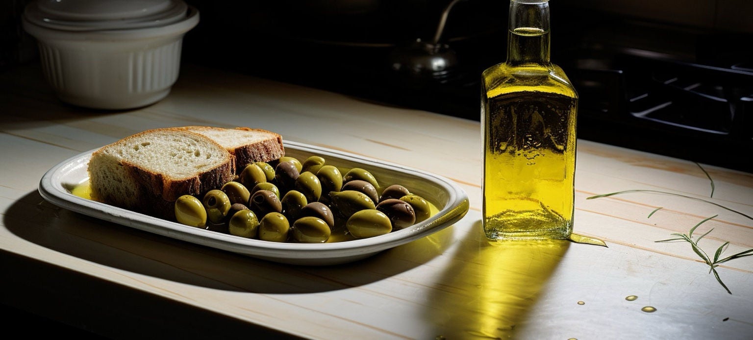 Bouteille d’huile d’olive posée à côté d’olives et de tranches de pain sur un plan de travail de cuisine