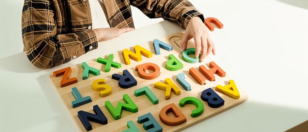 Puzzle en bois avec lettres colorées sur fond blanc