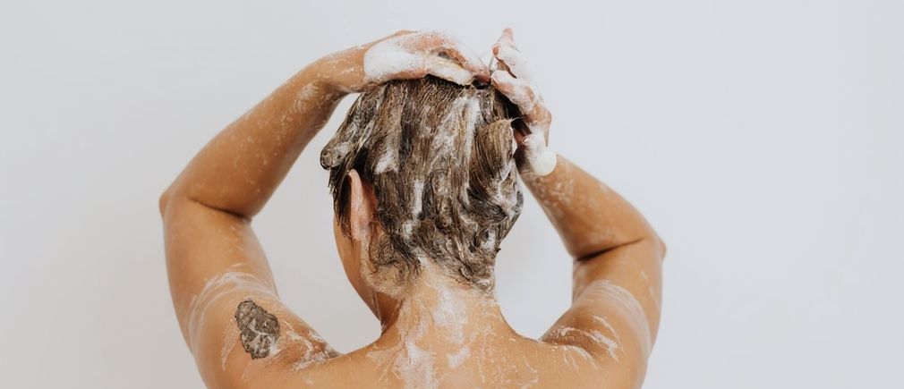 Personne lave ses cheveux avec du savon sur fond blanc