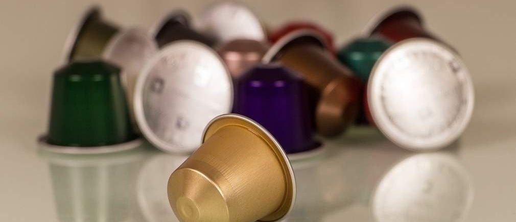 Capsules de café multicolores posées sur une table réfléchissante