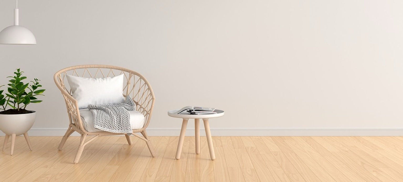Chaise en osier avec coussin blanc et livre sur table basse à côté d’une plante