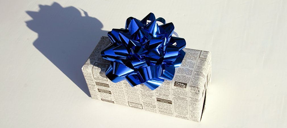 Paquet cadeau en papier journal avec nœud bleu