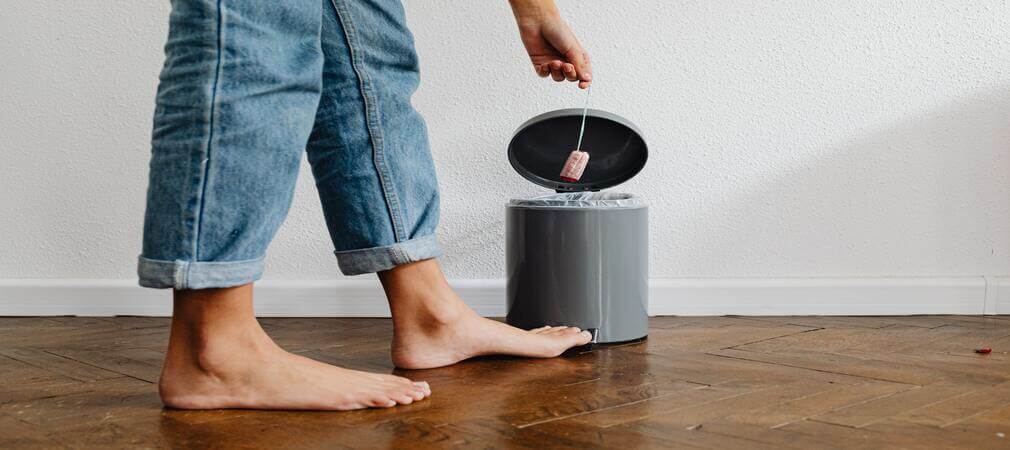 Main féminine jetant un tampon dans une poubelle à pédale