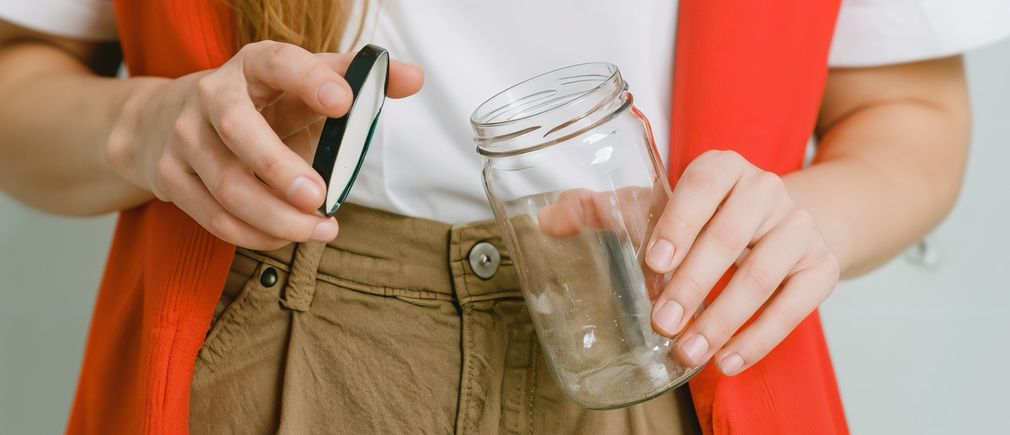 Main ouvrant un bocal en verre avec son couvercle