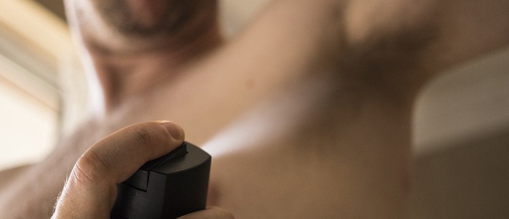 Homme utilisant un déodorant en aérosol sous les aisselles