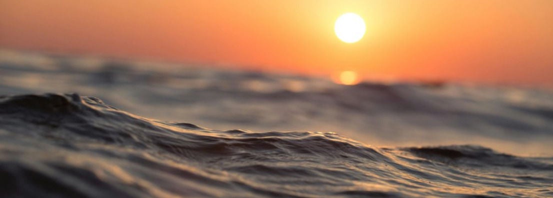 Vague au premier plan sous un coucher de soleil orange